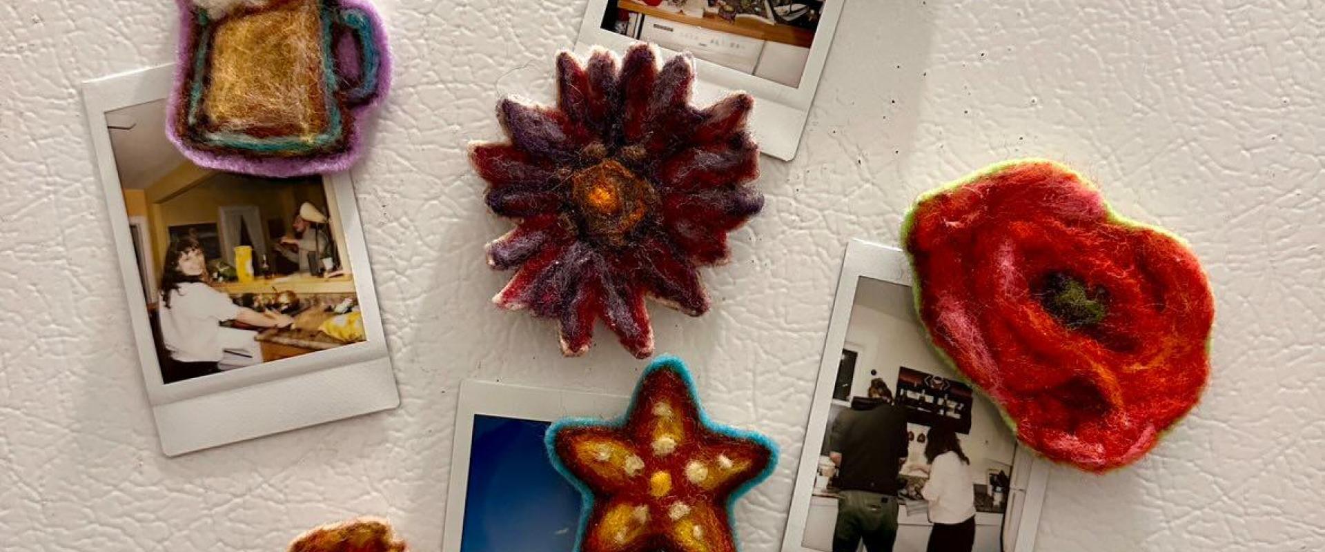 small hand felted magnets in the shapes of flowers and other objects on fridge door