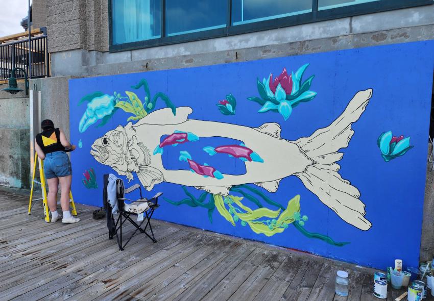 Maddy Filipps painting a mural on a Halifax Marriott Harbourfront wall