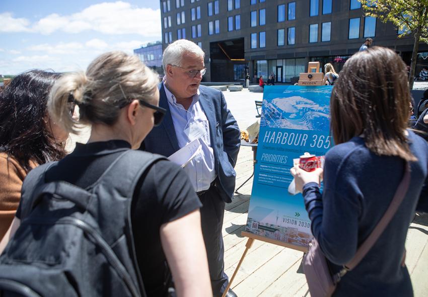 People discuss the Downtown Halifax Vision 2030 in front of the board that says "Harbour 365".