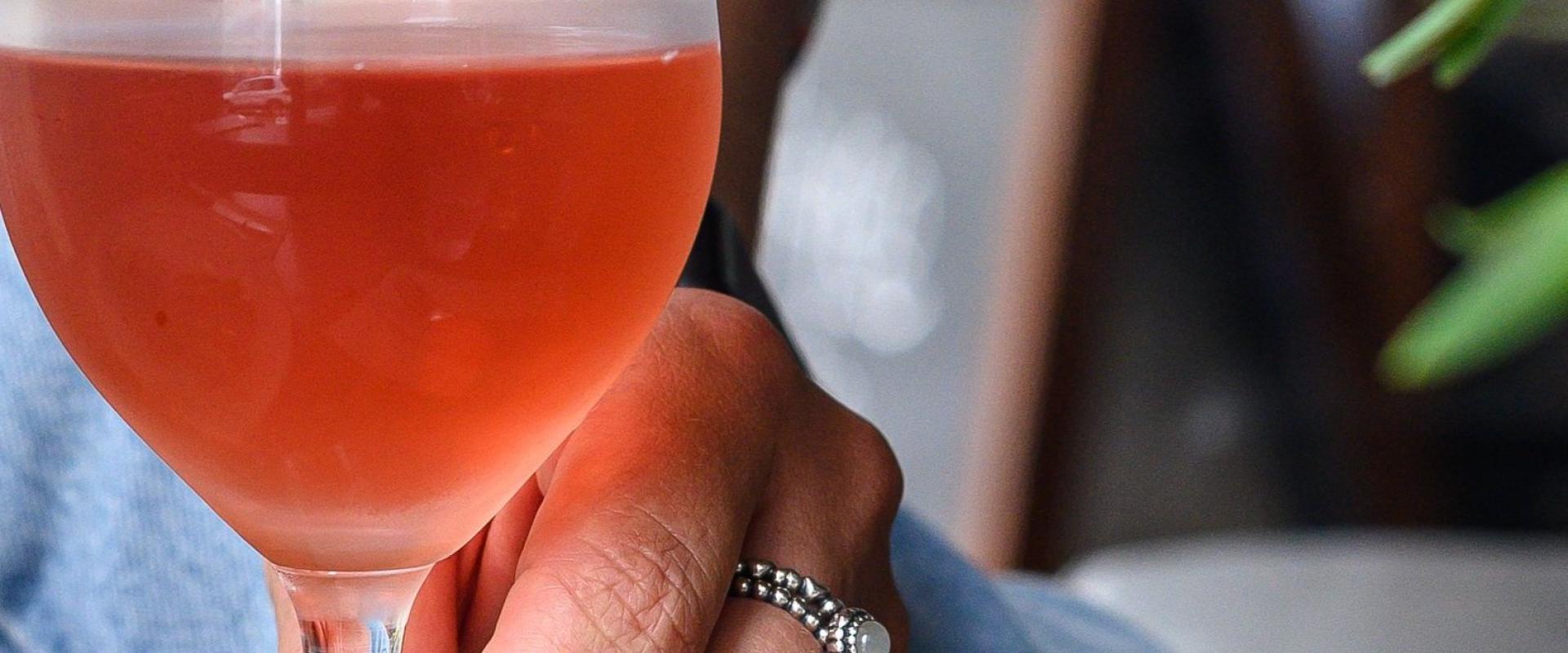 Person holding the stem of a glass of rose.