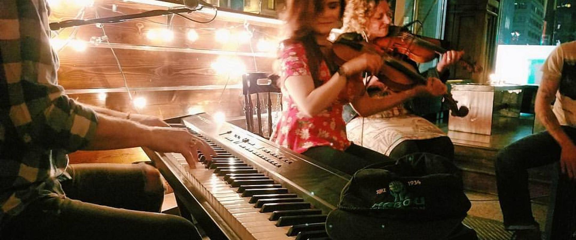 Two fiddle players and a keyboardist playing with low lights behind them.