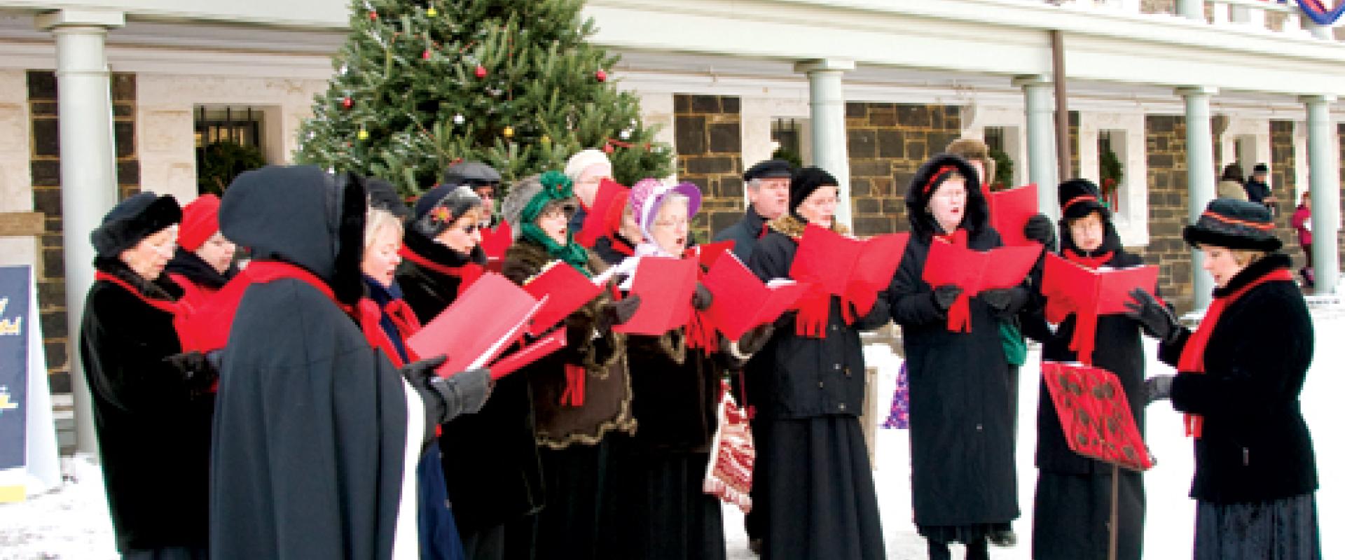 Choir dressed in period costume singing outside of the Cavelier building in the Halifax Citadel National Historic Site parade square.