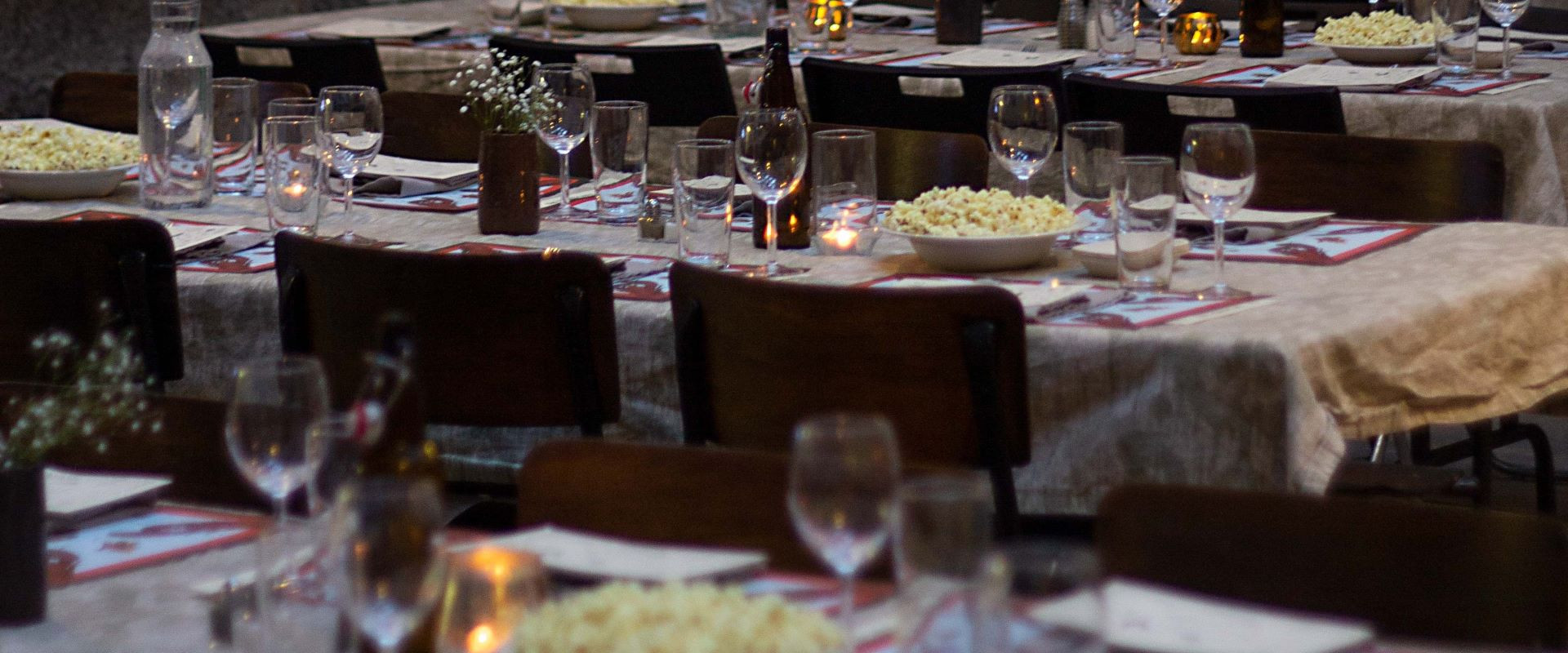 A photograph of long tables set for a classy dinner in a brick building.