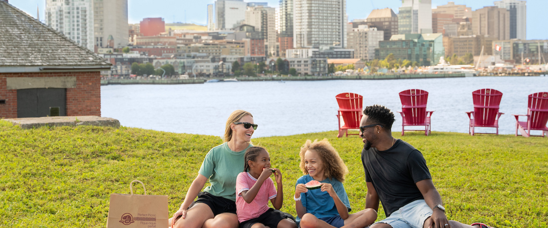 Family enjoying a picnic on Georges Island with Halifax skyline in the background.
