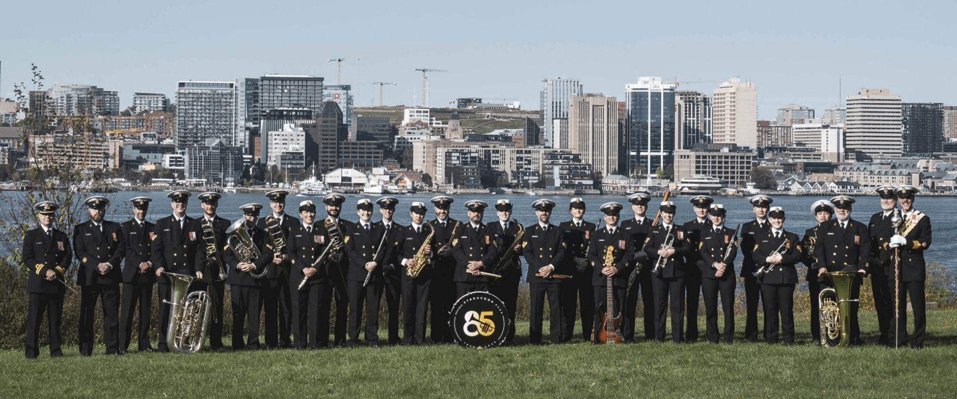 Members of the Stadacona Band pose for a unit photo with the Halifax Waterfront in the distance, taken in Dartmouth, NS, on 16 September 2025.Photo Credit: Corporal Gregory Cole, Canadian Armed Forces Photo