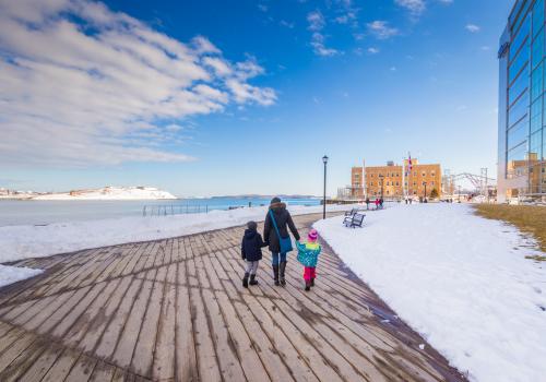 A family walking along a snowy boardwalk on the Halifax Waterfront. 
