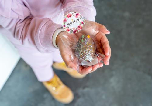 Chocolate egg in plastic cradled by a child's hands
