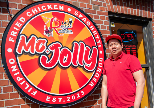 Jerrick Atienza, co-owner of McJolly, standing outside the restaurant with their sign