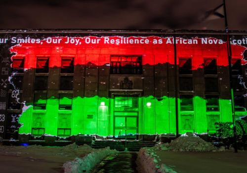 DELIGHTFUL DOWNTOWN light projection show with Pan-African flag and the words "Our Our Smiles, Our Joy, Our Resilience as African Nova Scotians"
