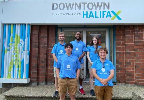Five members of the 2023 Downtown Halifax Crew posing for the camera in front of the DHBC office. 