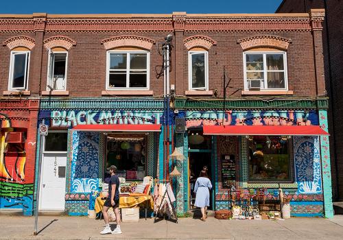 A person walks by the colourful storefront of The Black Market in Downtown Halifax. 