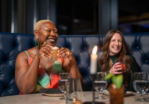 two women enjoying a laugh and a drink out.