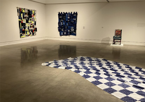 Installation view of textile and fiber art pieces on display in a gallery setting.