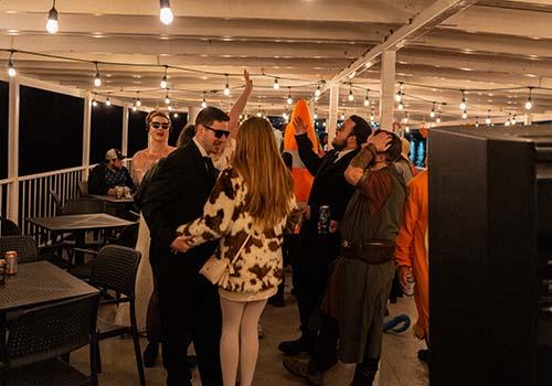 People in various halloween costumes dancing on a boat at night.