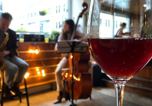 Glass of wine on the bar with musicians in the background.